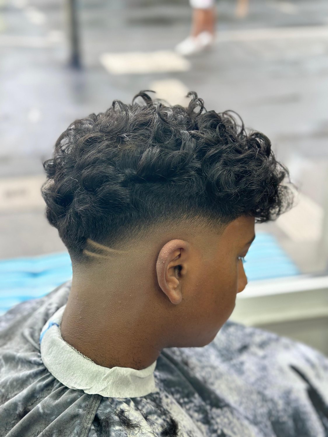 Lockiger Haarschnitt mit tiefem Fade
